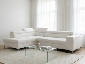Grand canapé d'angle blanc, salon minimaliste lumineux avec table en verre, tapis texturé et voilages blancs.