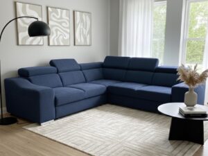 Salon contemporain avec grand canapé d'angle bleu, tapis géométrique beige, lampe noire et tableaux abstraits.