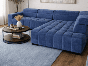 Canapé d'angle bleu texturé dans un salon moderne avec tapis assorti, table basse ronde et tableau abstrait.