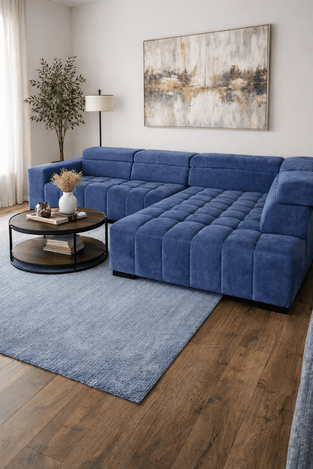 Canapé d'angle bleu texturé dans un salon moderne avec tapis assorti, table basse ronde et tableau abstrait.