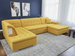 Canapé d'angle en U jaune moutarde dans un salon moderne avec mur bleu, tapis gris et lampadaire doré.