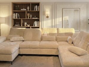 Grand canapé d'angle en velours côtelé beige dans un salon élégant avec éclairage chaleureux et plante verte.