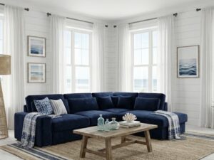 Salon côtier avec canapé d'angle bleu marine, table bois et déco bord de mer lumineuse avec vue sur l'océan.