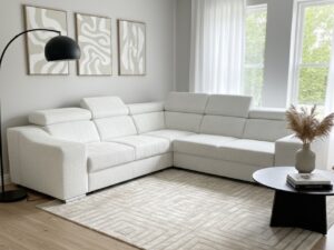 Salon moderne avec canapé d'angle blanc, tapis géométrique beige et lampadaire noir minimaliste.