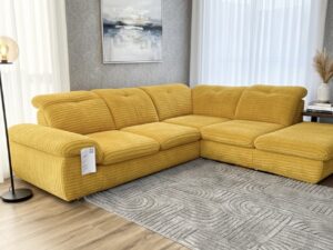 Grand canapé d'angle jaune en velours côtelé dans un salon élégant avec tapis gris texturé et parquet.