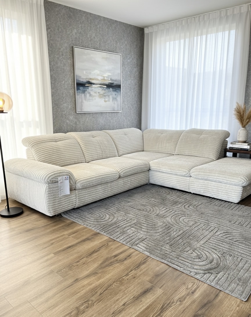 Canapé d'angle en velours côtelé beige dans un salon moderne avec tapis gris à motifs et mur texturé.