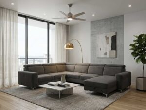 Salon moderne avec canapé d'angle gris, table basse en marbre, lampe dorée et plante verte devant une grande baie vitrée.